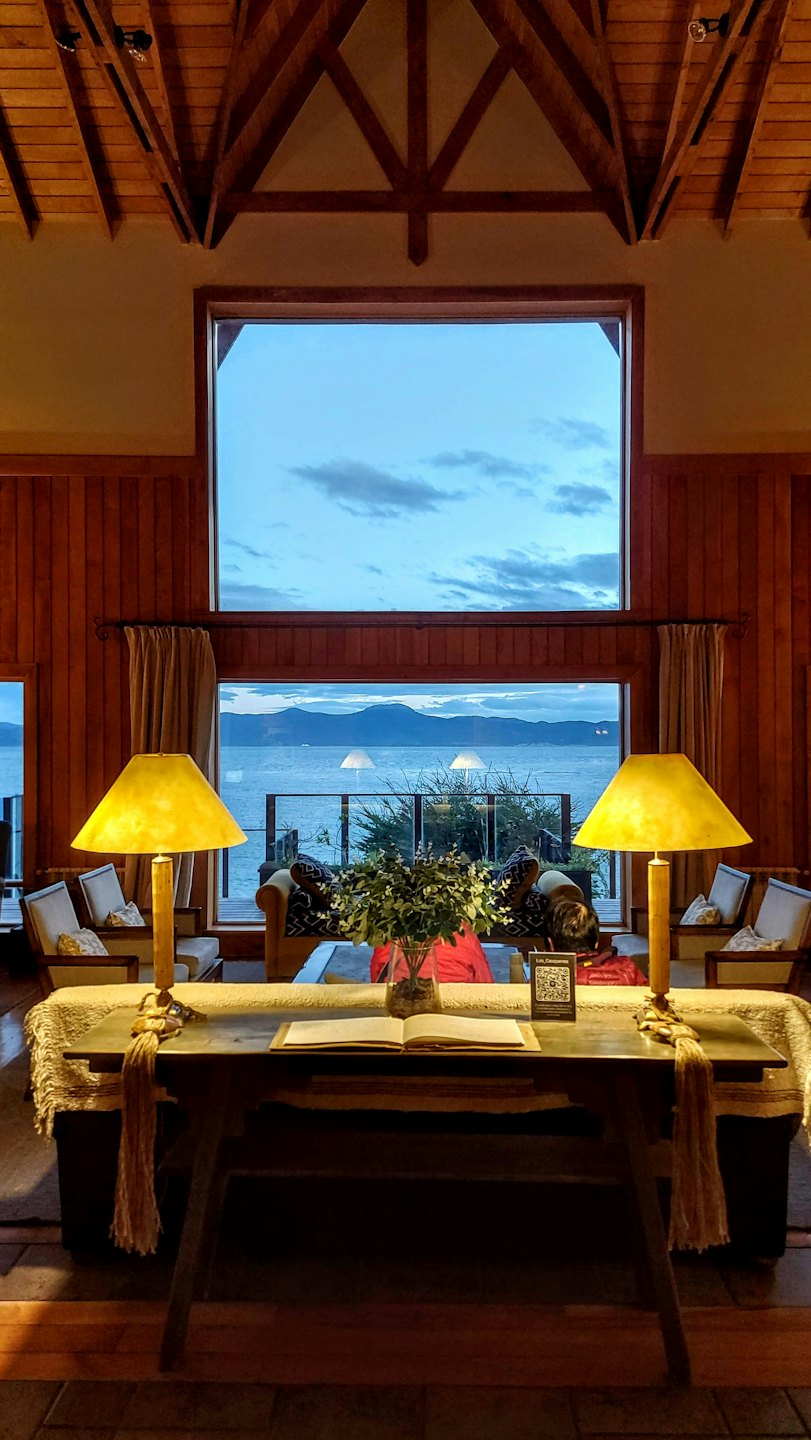 Gemütliches Lodge-Interieur mit einem Tisch am großen Fenster mit Blick auf den See.